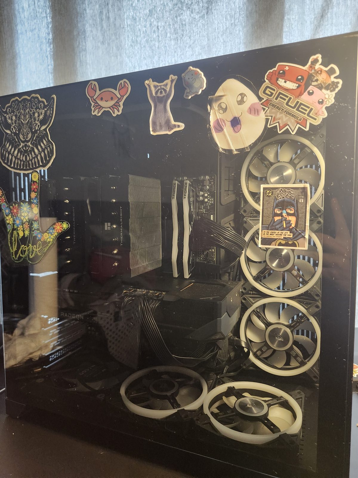 Glass front of a dual-chamber case with stickers on the panel. White fans and a Radeon graphics card are visible through the glass.