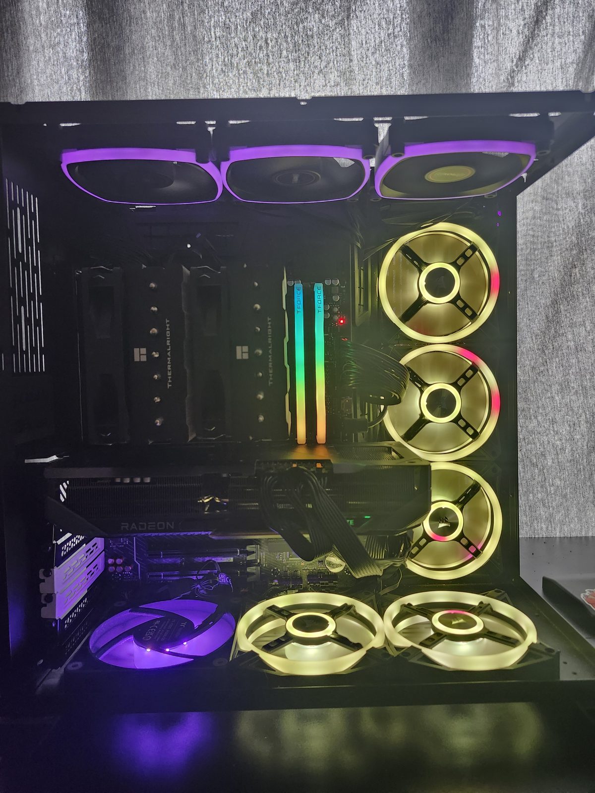 Another angle of the same lit interior, showing the Thermalright cooler, T-Force RGB memory, the Radeon graphics card, and Corsair fans.