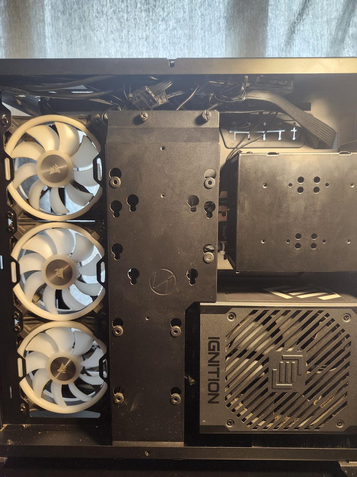 Back chamber with a cover plate over the cables. Three white Corsair fans are on the left, and an Ignition power supply is at the bottom right.