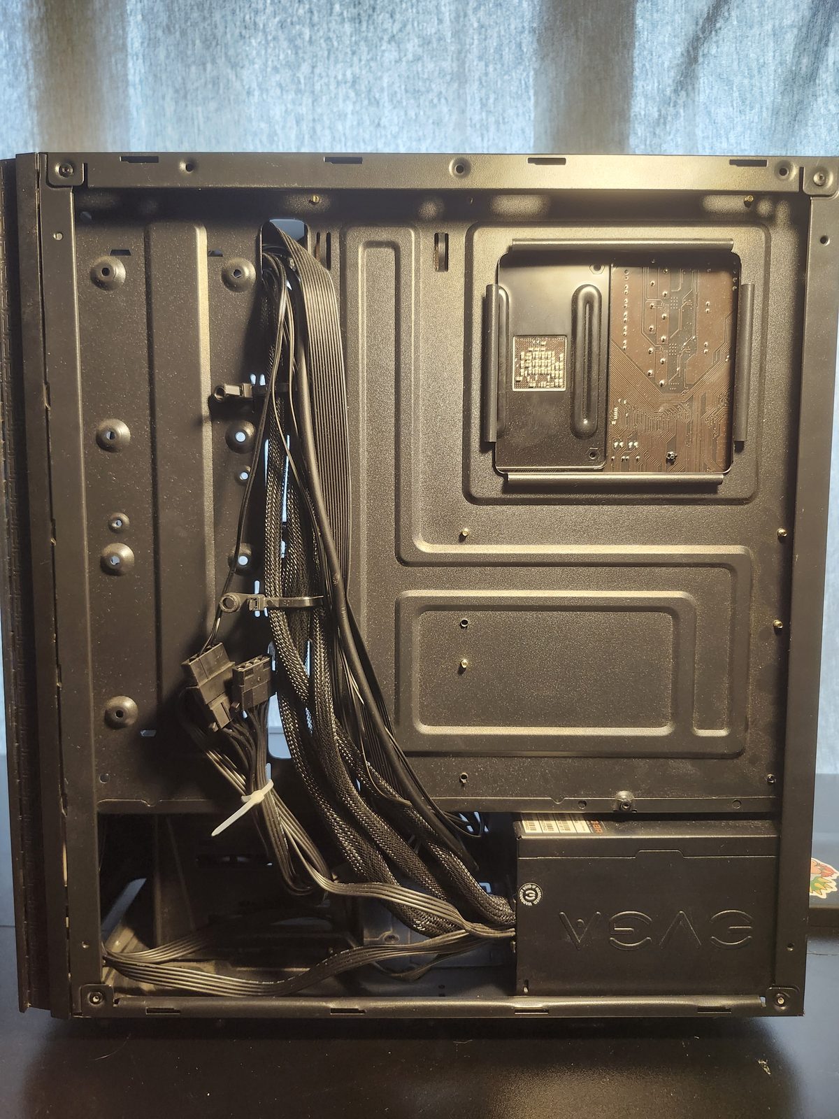 Back of the same mid-tower with the side panel off. Power cables are bundled down the left side, and an EVGA power supply is mounted at the bottom.