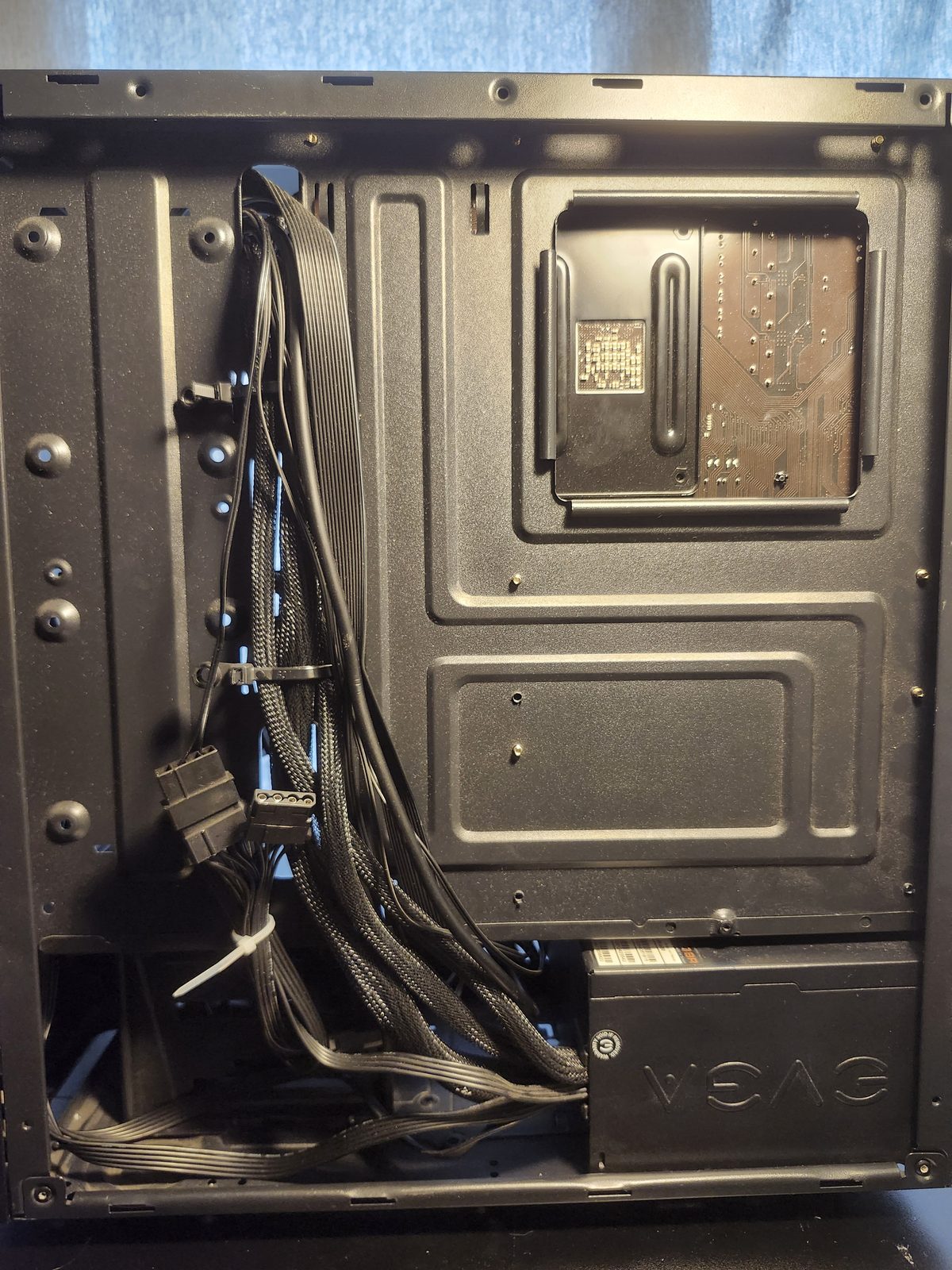 Closer view of the back-panel cable routing. The sleeved cables are gathered in a bundle beside the EVGA power supply.